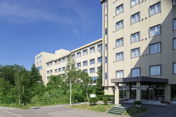 Ett hotell med flera våningar, en slät fasad, stora fönster och en ingång som är skyddad av ett tak.