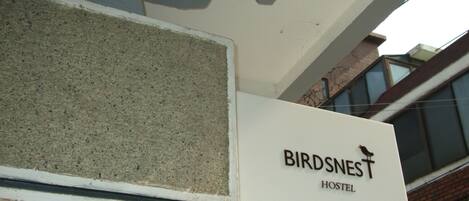 A sign for 'Birdsnest Hostel' mounted on a building facade.