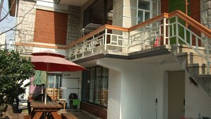 En bygning med flere etager, en balkon, et udendørs siddeområde og en trappe.