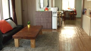 En stue med sofa, sofabord i træ, en lille plante, et skab og et køleskab.