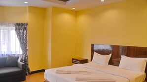 A hotel room with a bed, a nightstand, a sofa, and a window with curtains. - Taj Place Residency (Pattaya)