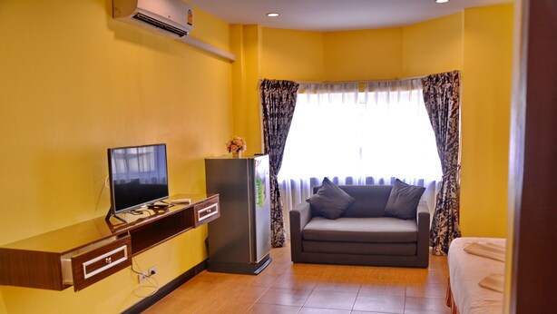 A room with a TV, a refrigerator, a sofa, and a bed. - Taj Place Residency (Pattaya)