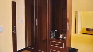 A room with a wooden wardrobe, a small shelf with toiletries, and a mirror on the wall. - Taj Place Residency (Pattaya)