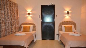 Una habitación de hotel con dos camas, cada una con cabecera, mesita de noche y lámpara.