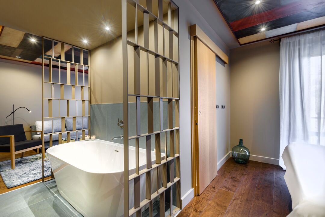 A modern bathroom with a freestanding bathtub, a wooden floor, and a glass partition.