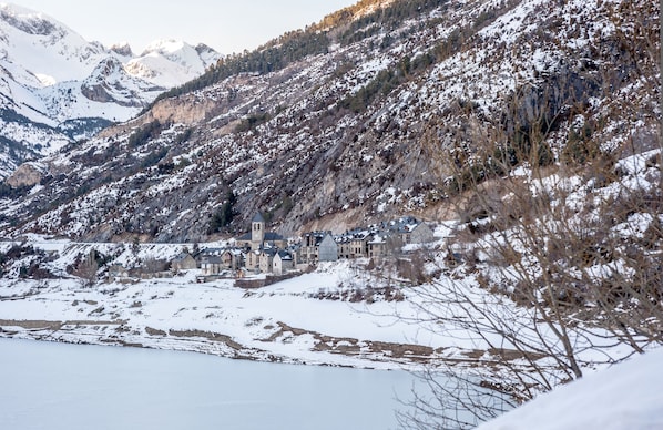 Un pueblo en la montaña cubierto de nieve, con edificios agrupados a lo largo de un río.