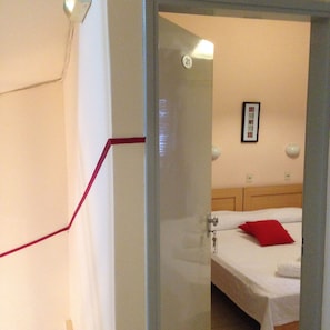 Hotellihuone, jossa on sänky, punainen tyyny, seinällä oleva kehystetty kuva ja ovi, jossa on numero 21.