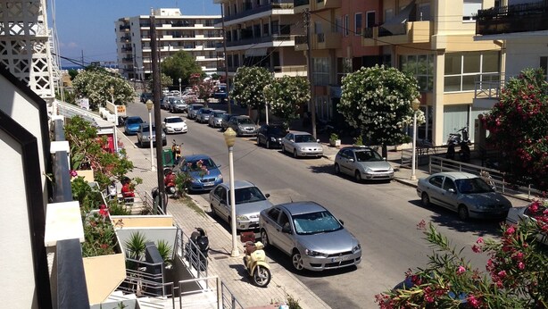 A street view with parked cars, buildings, and flowering plants. - Zefyros Hotel (Rhodes)