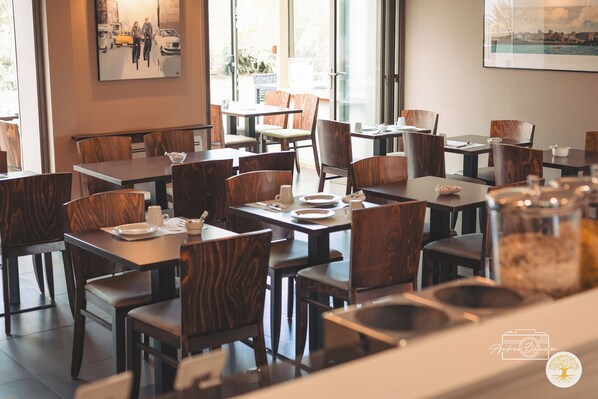 A restaurant interior with wooden tables and chairs, a coffee station, and artwork on the walls. - Hôtel Chantereyne (Cherbourg-en-Cotentin)