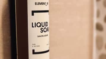 A bottle of Element liquid soap on a tiled wall.