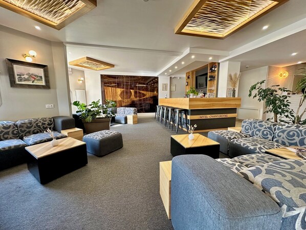 A modern hotel lobby with sofas, a bar area, and a large window.