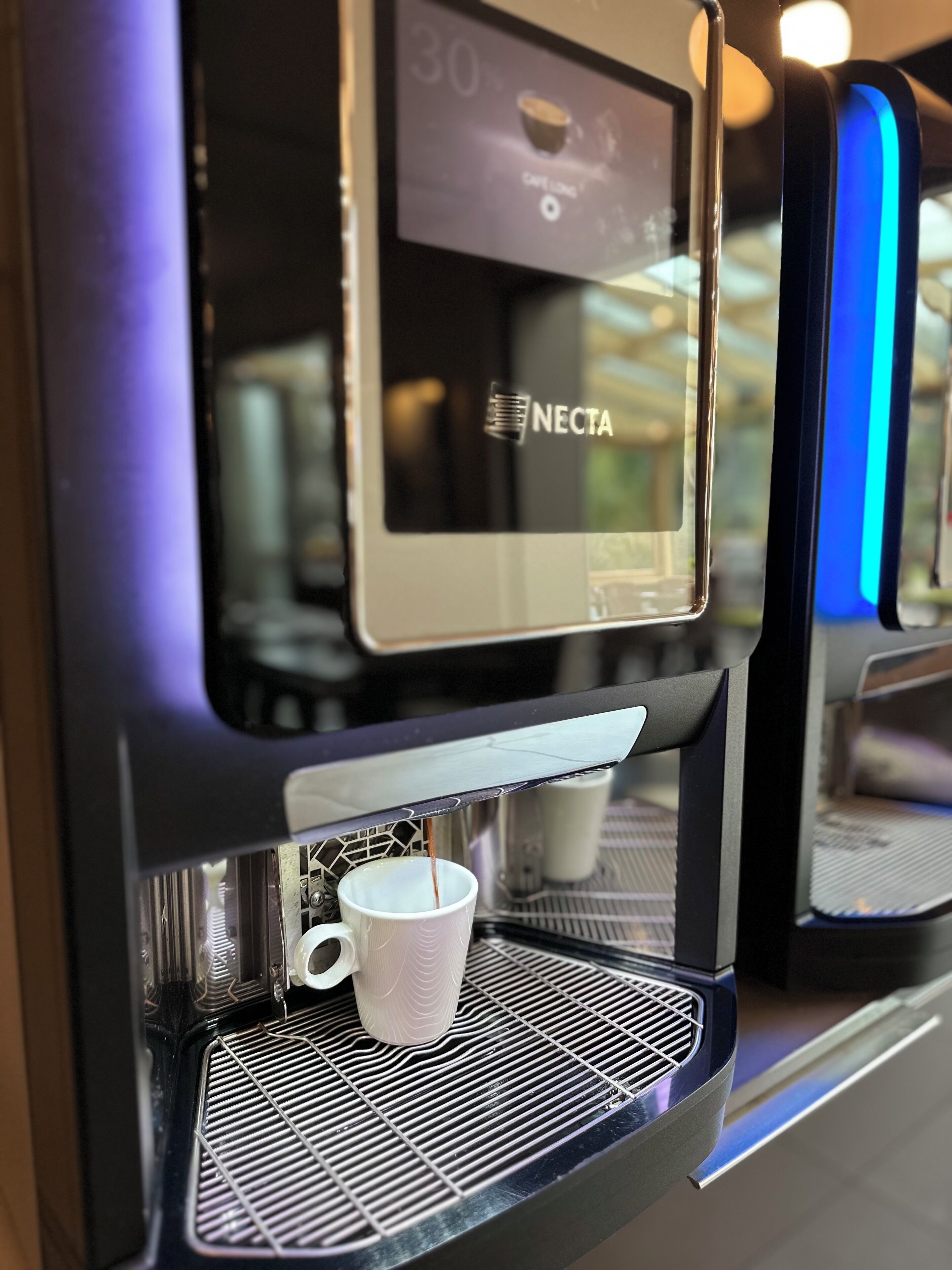 A coffee machine with a digital display and a cup placed underneath.