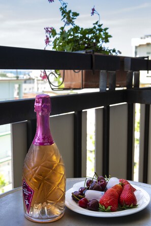 A bottle of champagne, a plate with strawberries and grapes, and a potted plant on a balcony. - Hotel Miramare et de la Ville (Rimini)