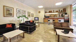 Un vestíbulo de hotel con área de bar, disposición de asientos y obras de arte en las paredes.