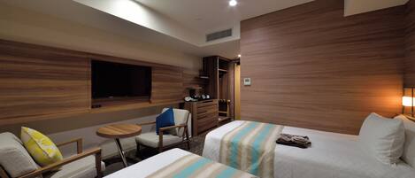 A hotel room with two beds, a TV, a desk, and a chair.
