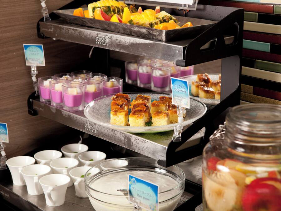 Buffet com diversos alimentos, incluindo frutas, sobremesas e bebidas.