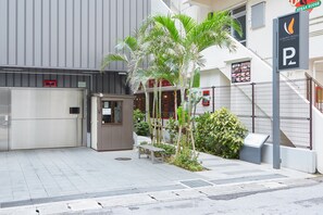 L’entrée d’un hôtel, avec un palmier, un banc et une enseigne indiquant un restaurant servant des steaks.