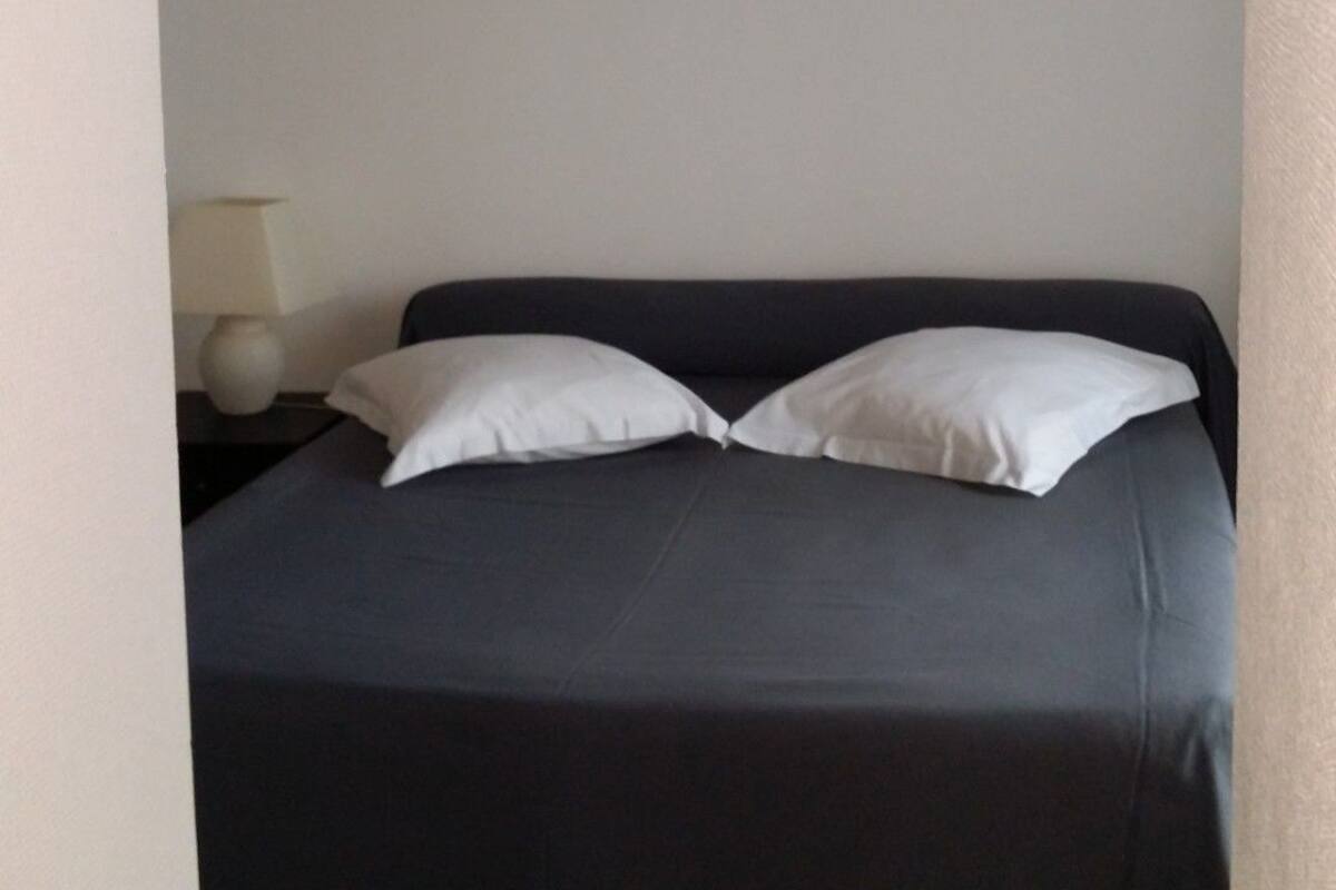 A bed with a dark cover and two white pillows, positioned under an arched ceiling.