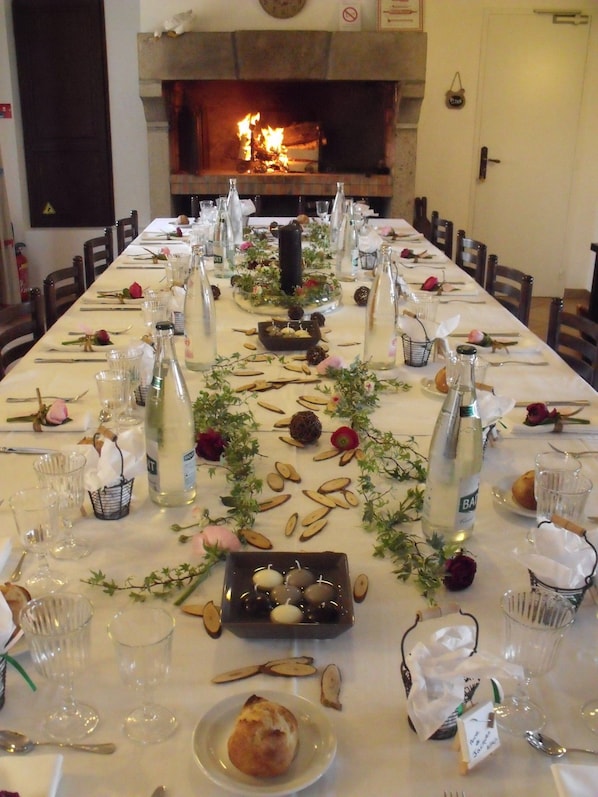 A long dining table set for a meal with bottles, glasses, and a central decorative piece.