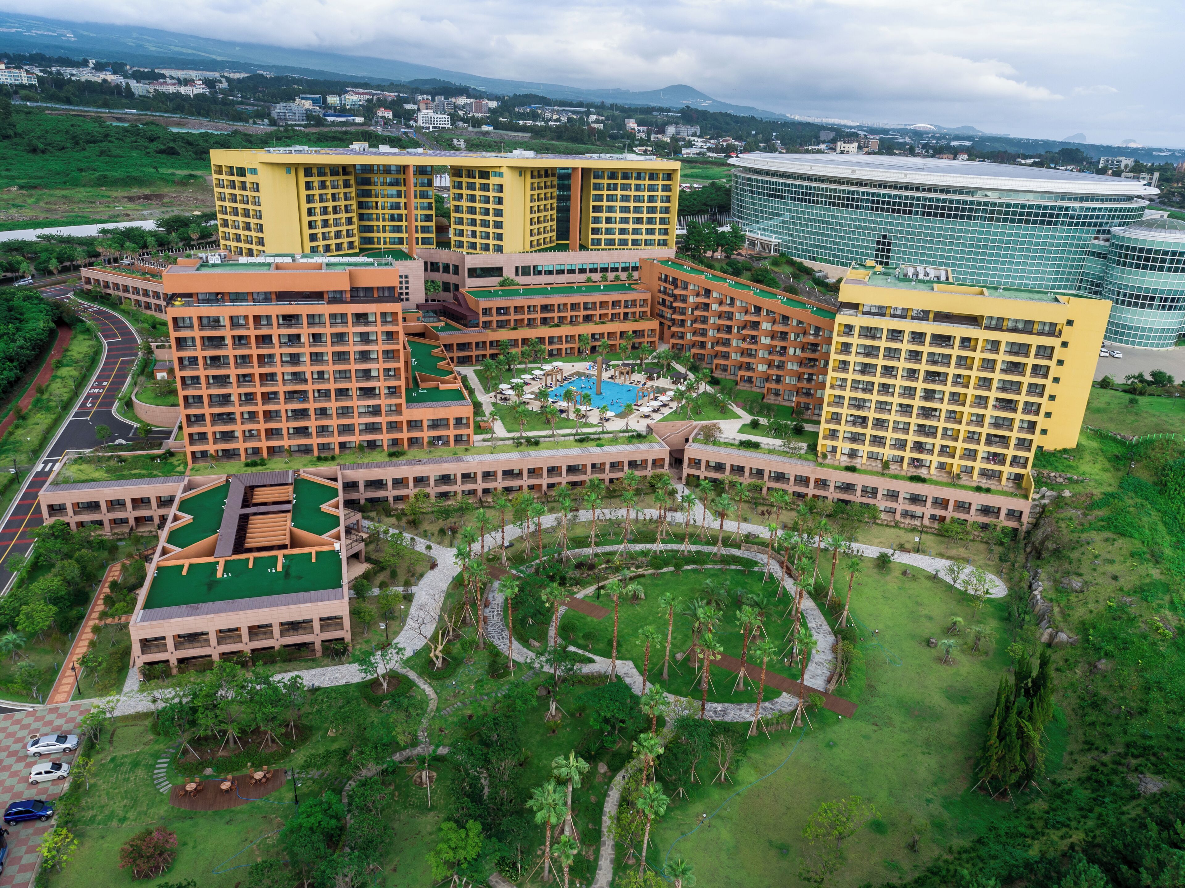 Un gran complejo hotelero con varias edificaciones, piscina y jardines ajardinados.