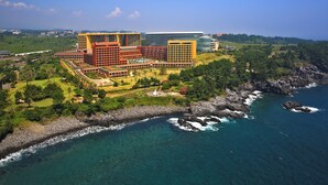 Un hotel costero con varias edificaciones, un jardín ajardinado y un litoral rocoso.