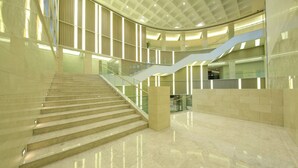 Un interior moderno con techo curvo, una escalera central y barandilla de vidrio.