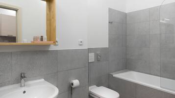 A modern bathroom with a sink, toilet, and bathtub.