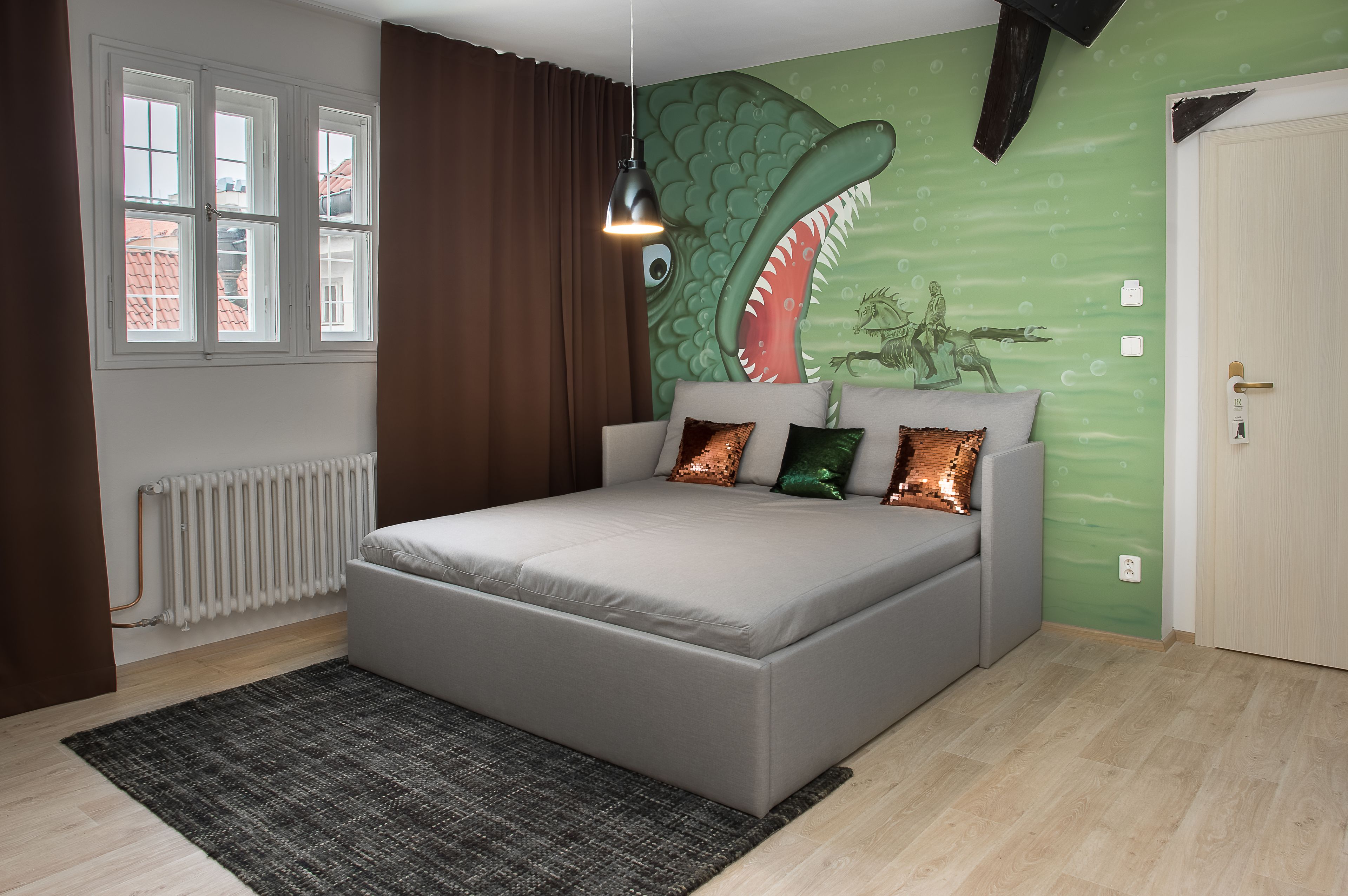 Un dormitorio con una cama grande, un mural verde en la pared, una ventana con cortinas marrones y un radiador.