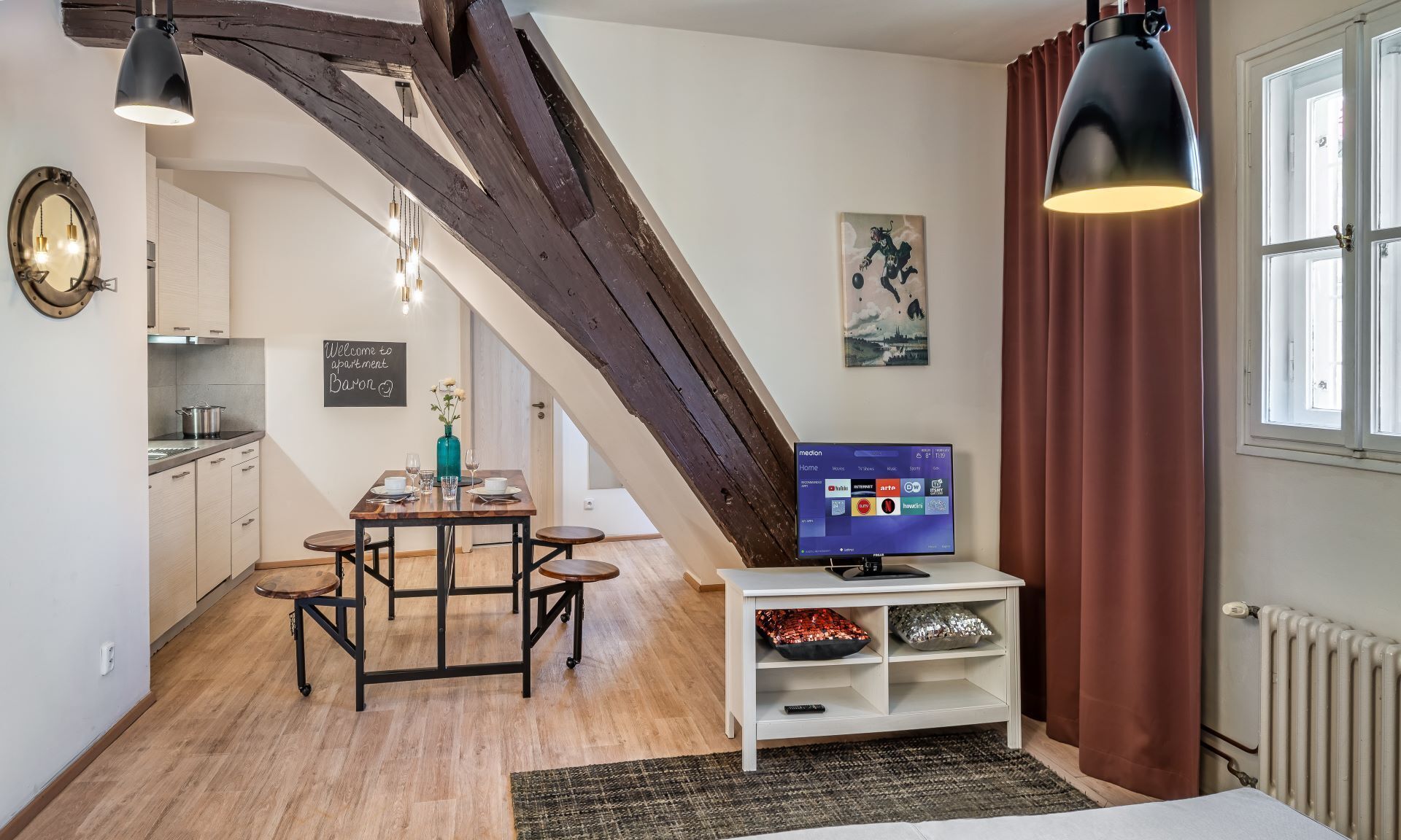Apartamento moderno con comedor, cocina y televisor sobre un soporte.