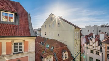Stadtansicht mit Gebäuden und roten Ziegeldächern unter blauem Himmel.