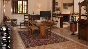 A dining area with a wooden table and chairs, a television, and a fireplace. - Relais La Mimosa (Sabaudia)