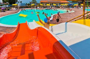 Un parque acuático con una piscina grande, un tobogán de agua y varias sombrillas.