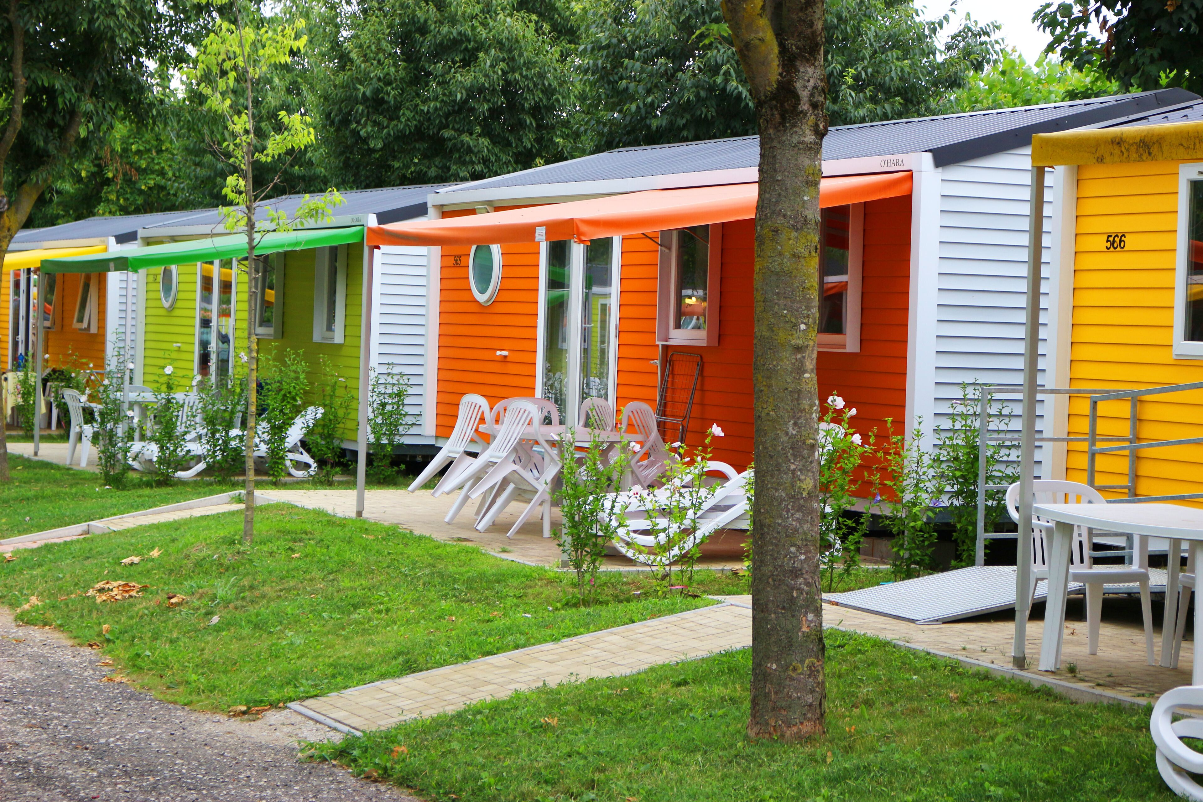 Een rij kleurrijke stacaravans met buitenzitplaatsen.