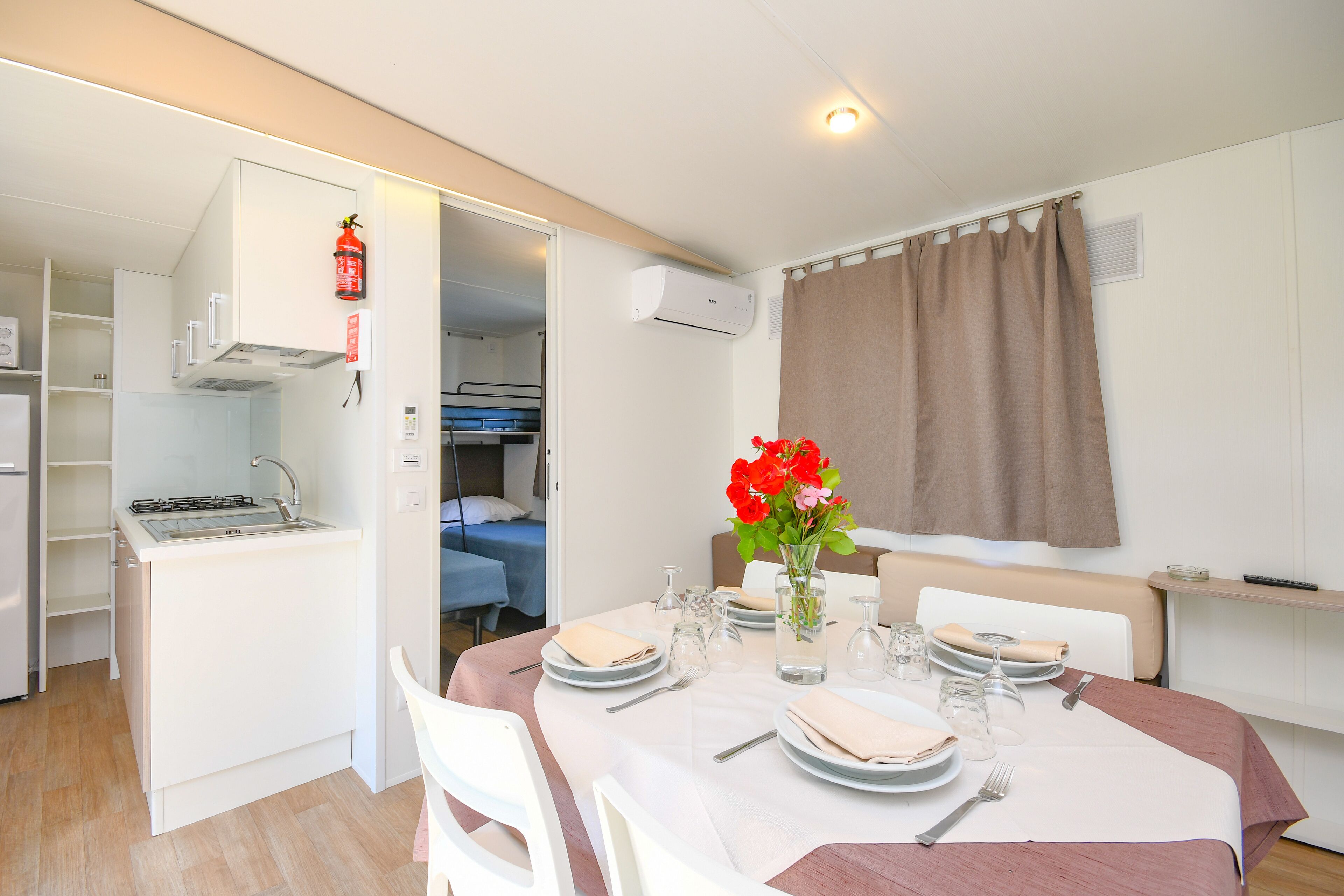 A compact room with a kitchenette, dining area, and a bed.