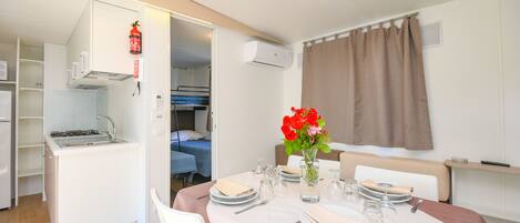 A compact room with a kitchenette, dining area, and a bed.