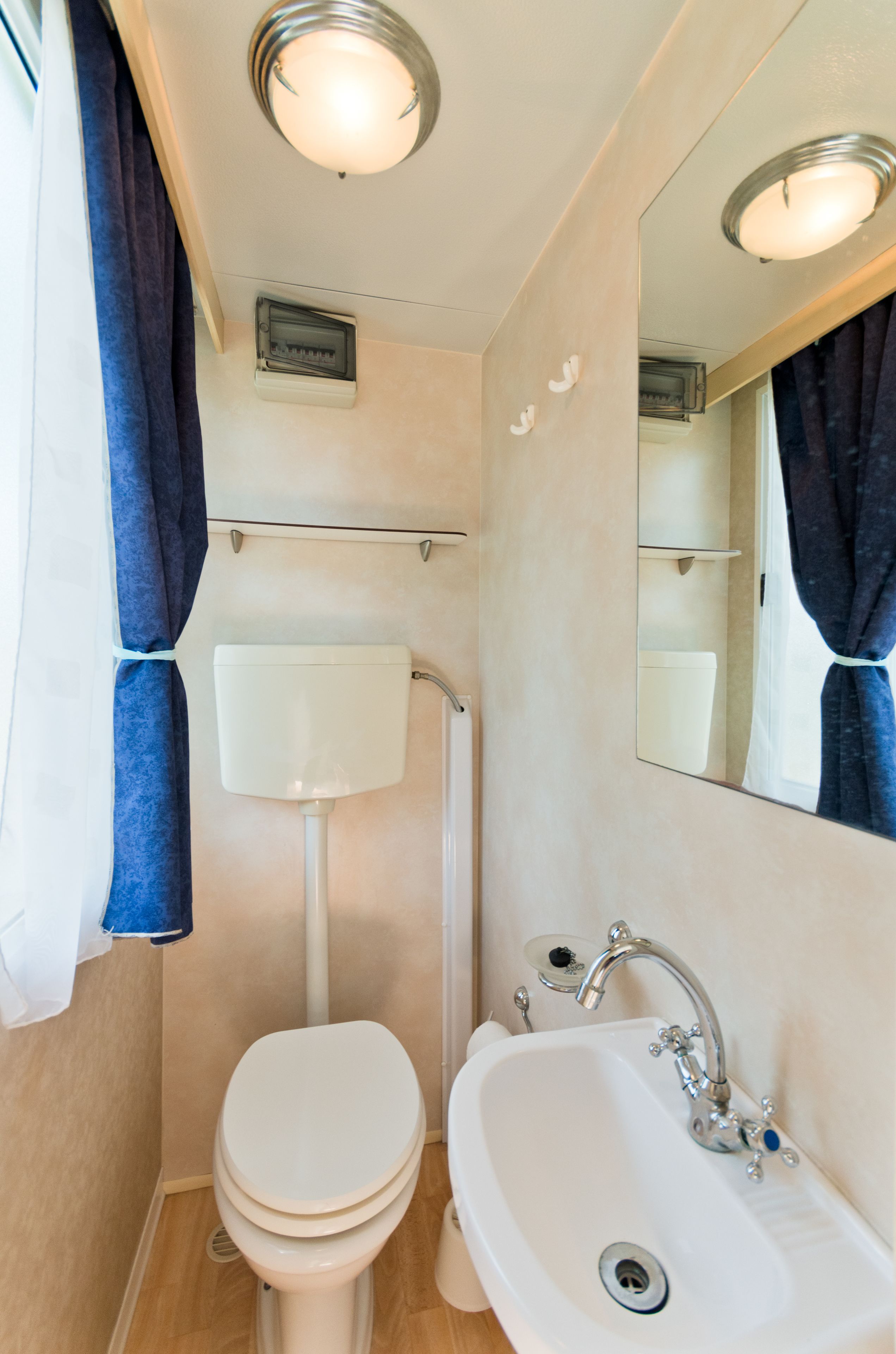 A compact bathroom with a toilet, sink, and mirror.