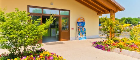 A building with a wooden facade, a glass entrance, and a flower garden in front.