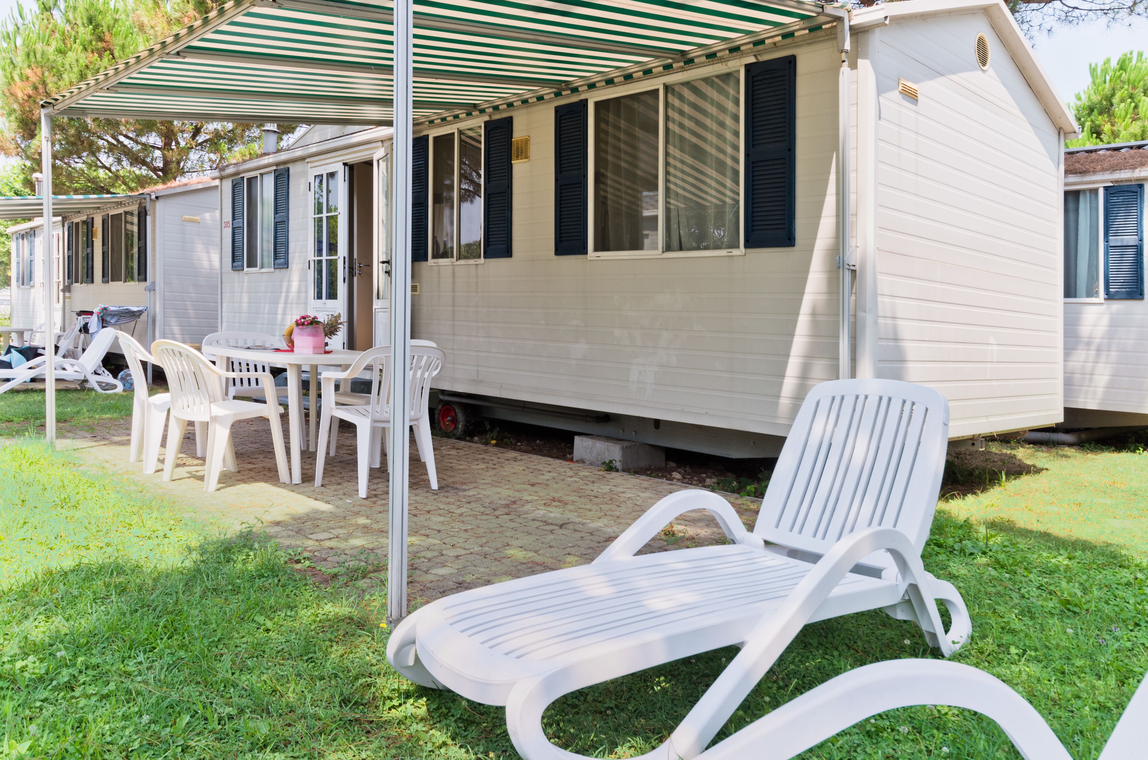 Une maison mobile dotée d’un patio couvert, d’un espace salon extérieur et d’une petite table.