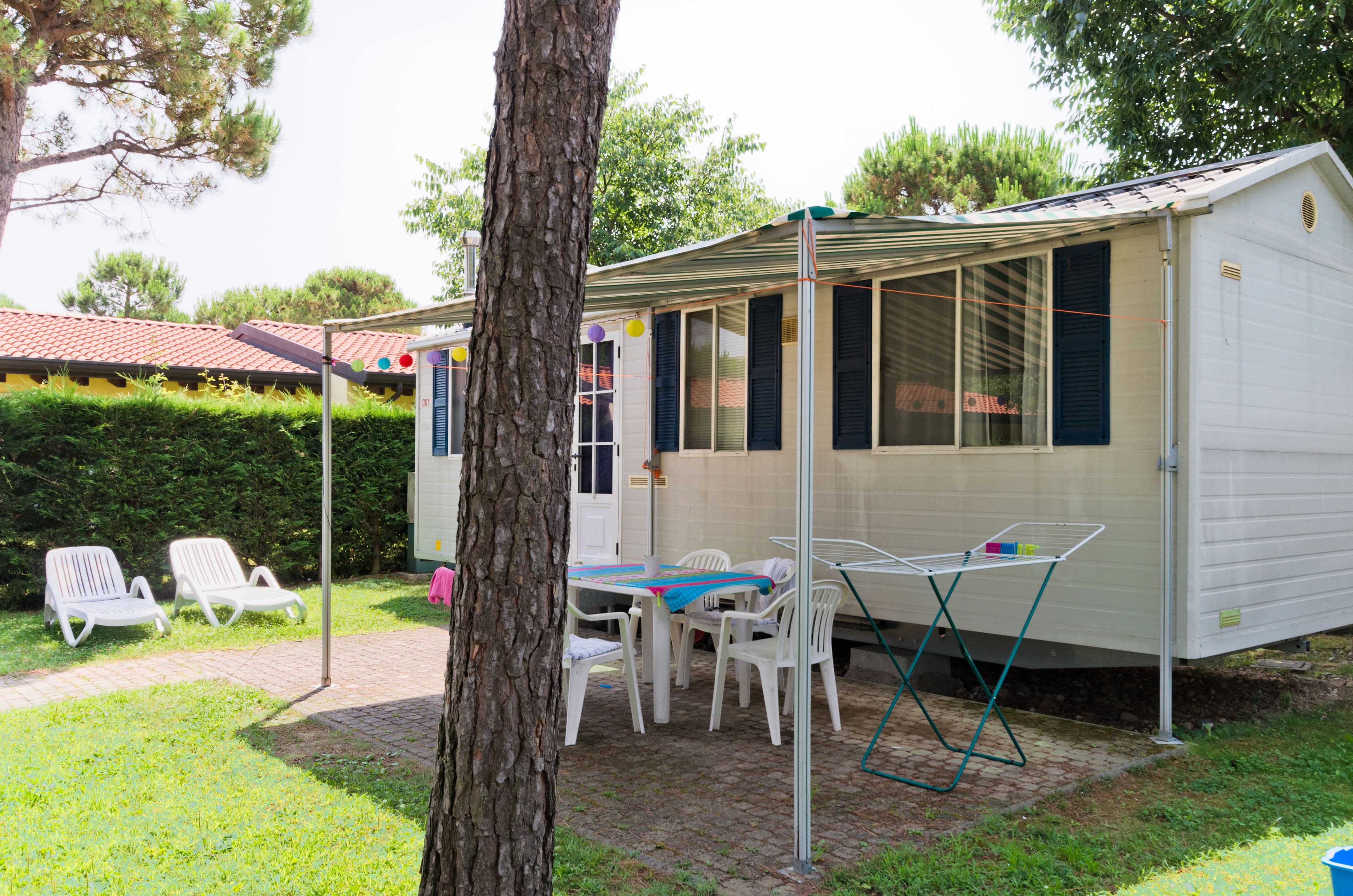 A mobile home with a patio area, including a table and chairs, and a small garden.
