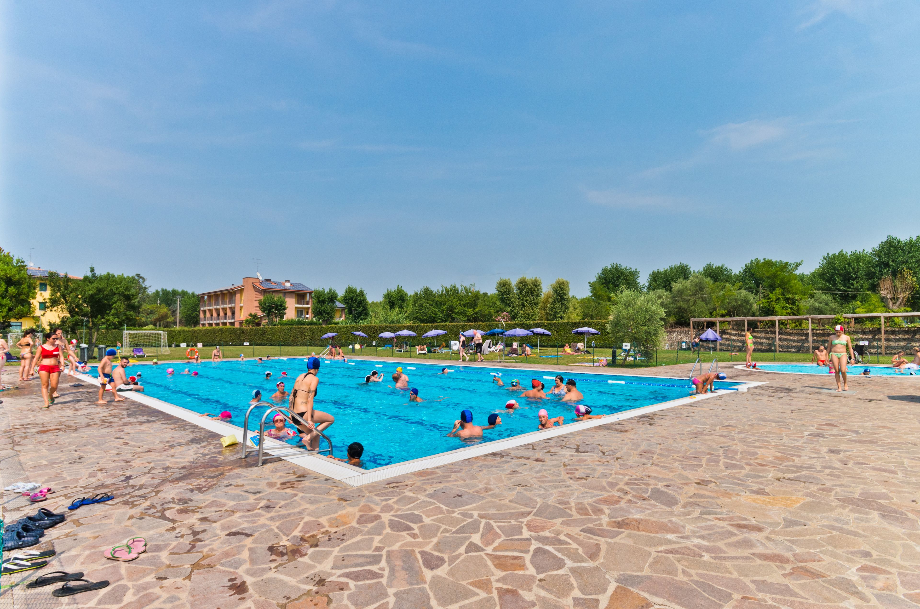 A swimming pool area with multiple pools, stone flooring, and umbrellas.
