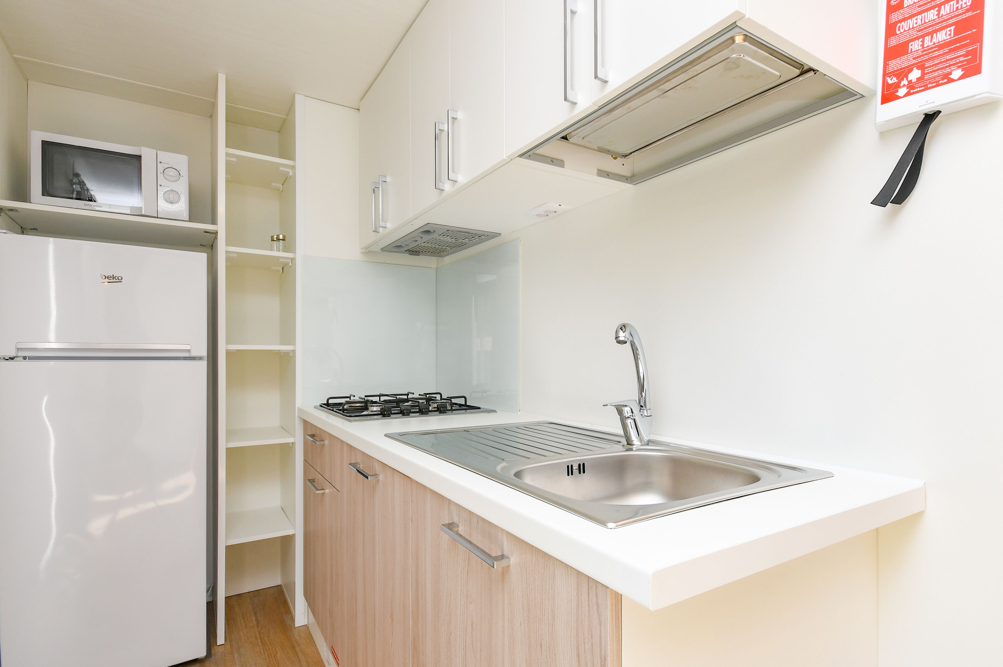 A compact kitchen with a built-in microwave, a gas stove, and a stainless steel sink.