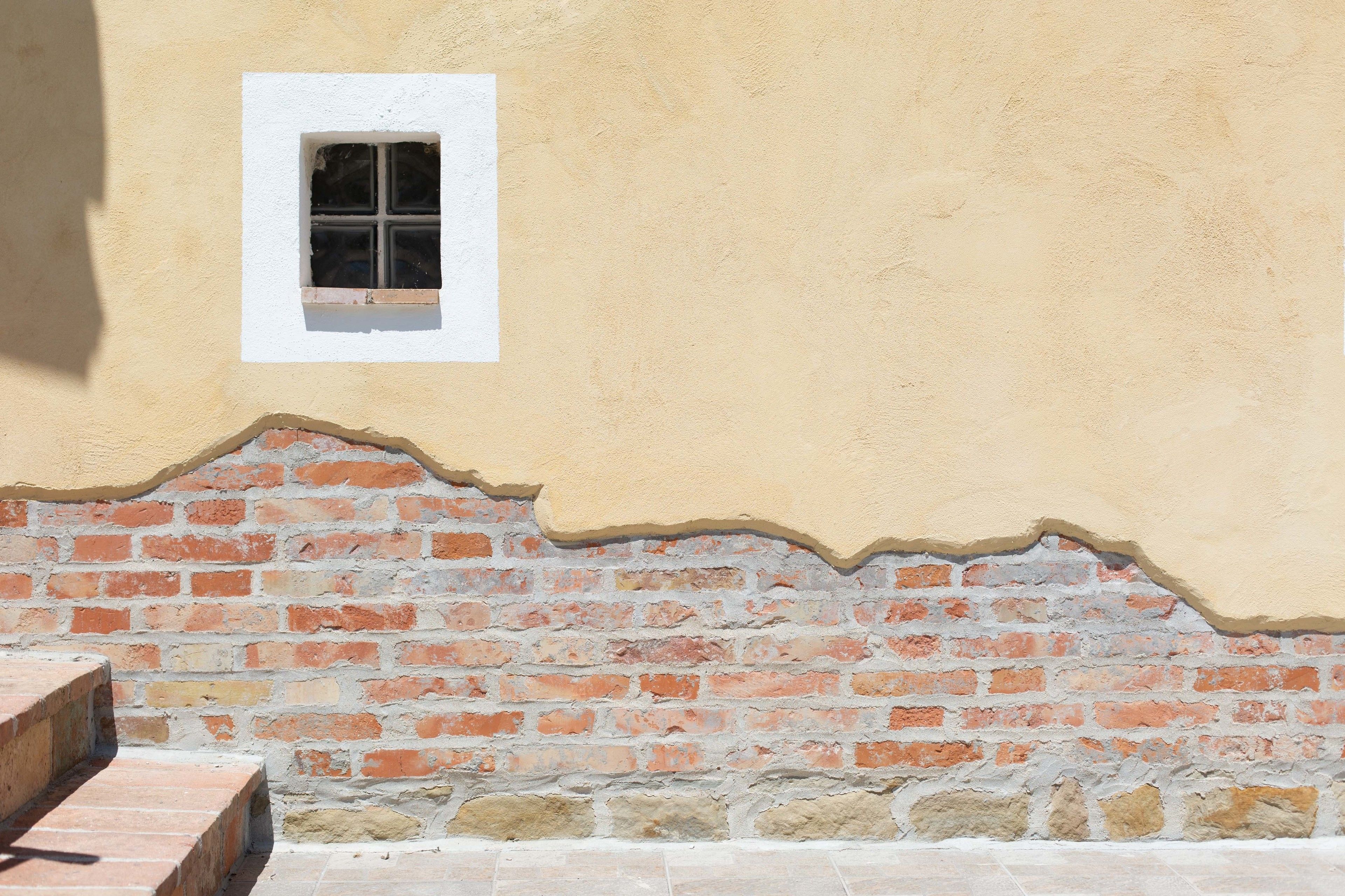 A wall with a window and a brick base.