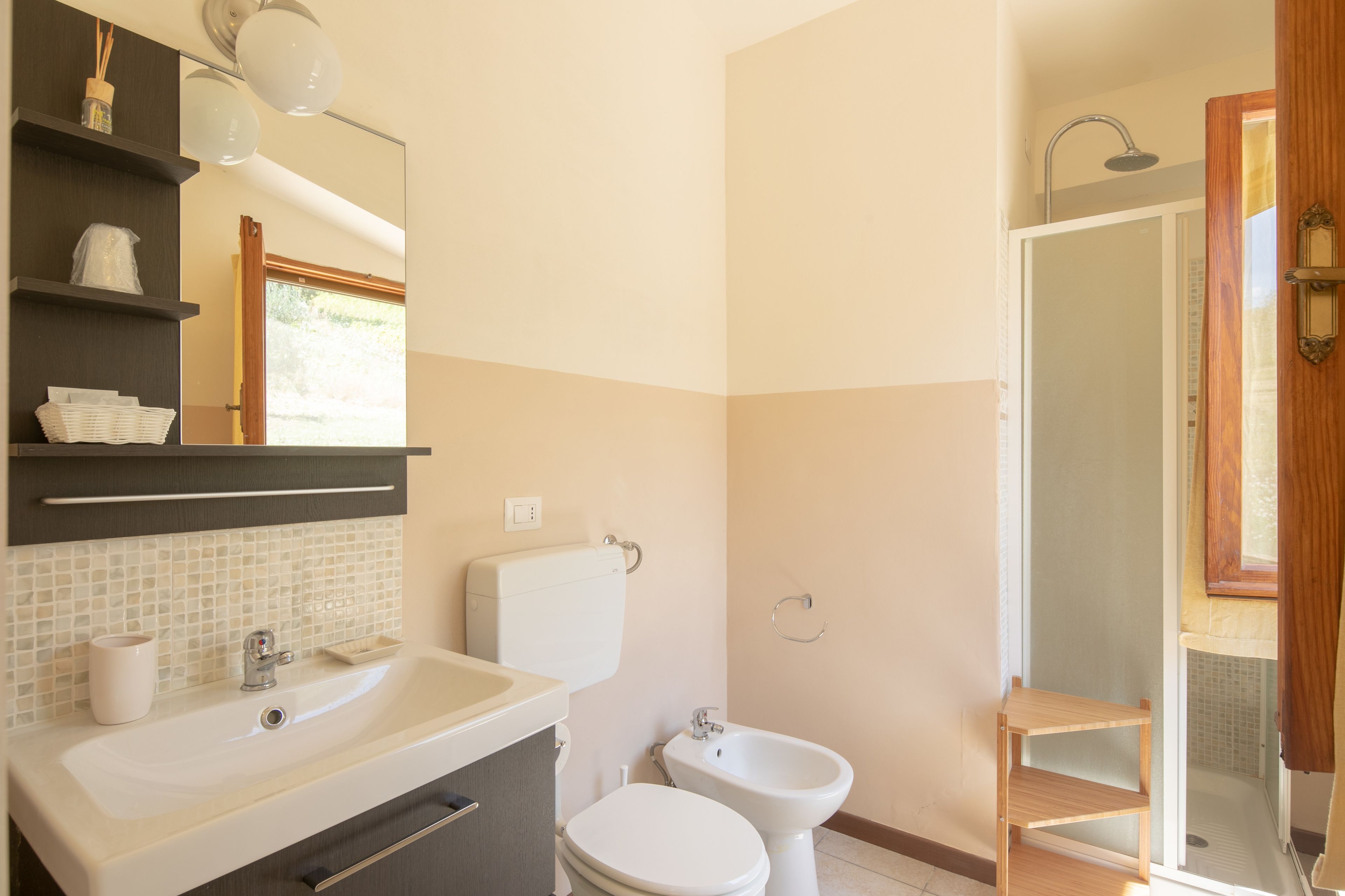 A bathroom with a sink, toilet, bidet, and a shower area.