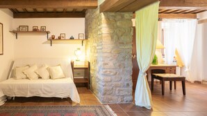 Une pièce confortable avec un lit, un mur en pierre, un bureau et une chaise.