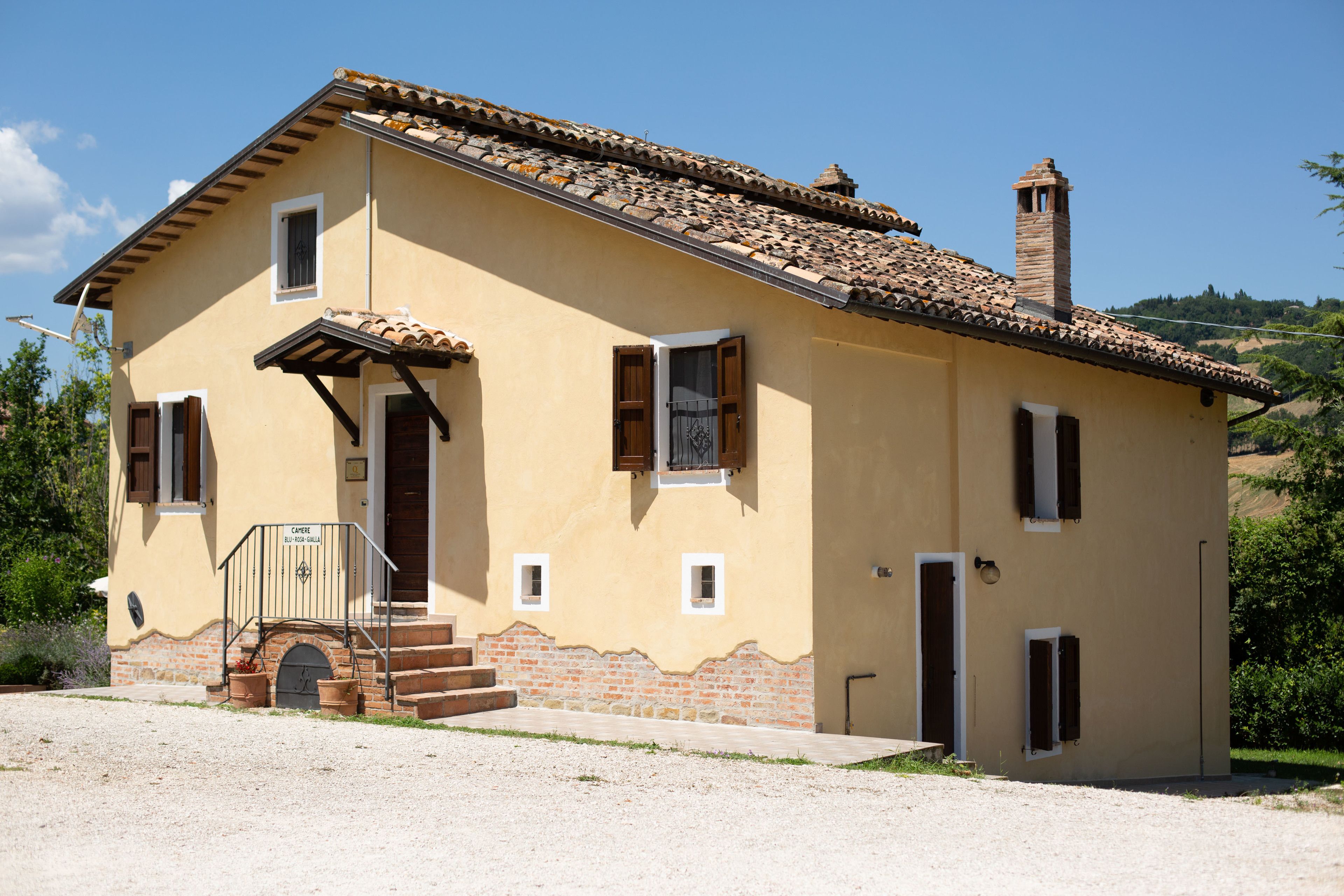 A two-story building with a tiled roof, a chimney, and a small porch with steps leading to the entrance.