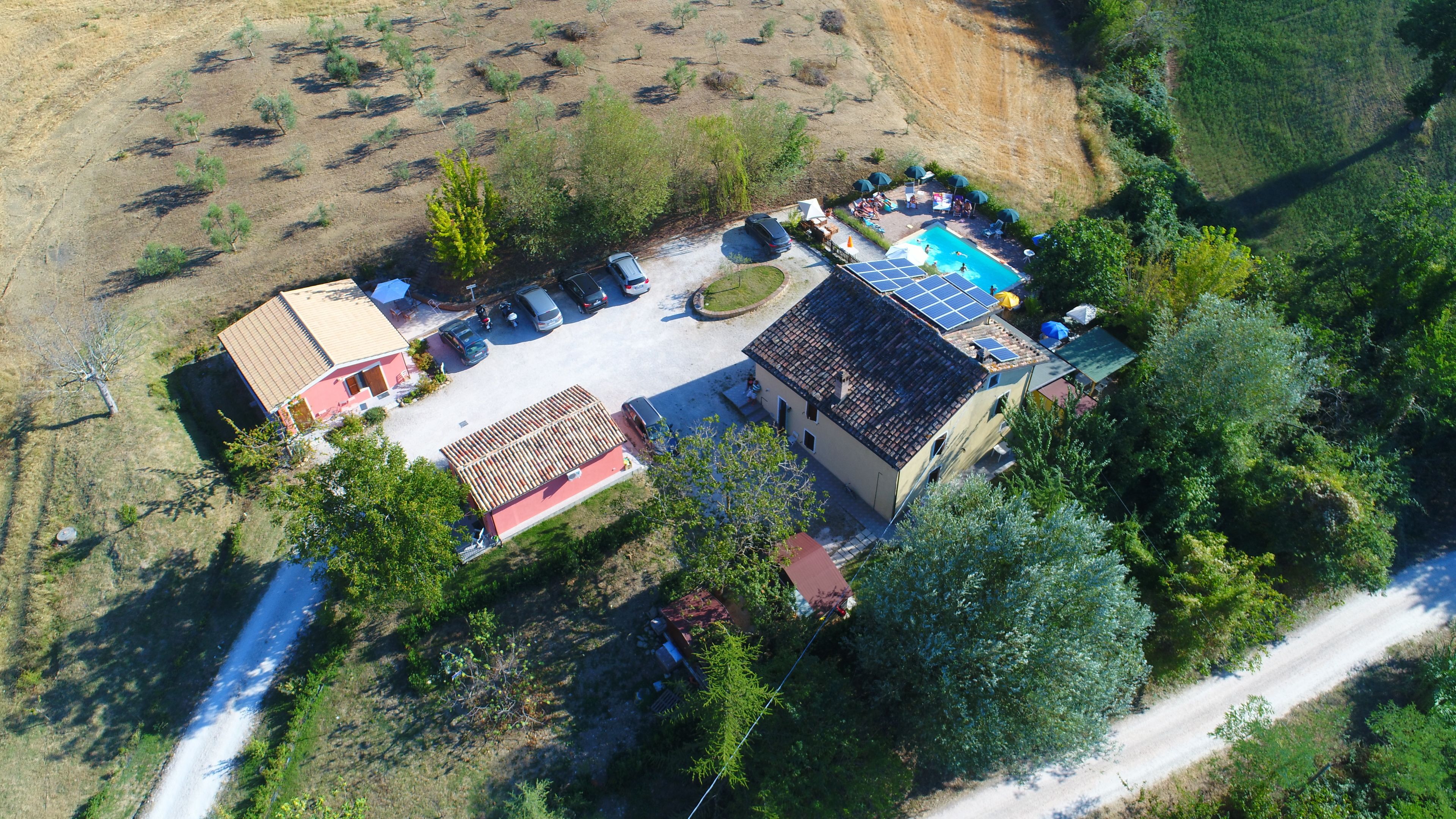 An aerial view of a property with a swimming pool, solar panels, and a parking area.
