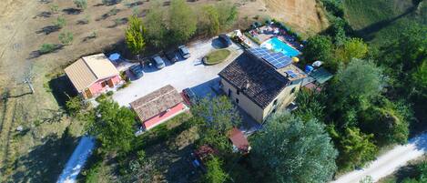 An aerial view of a property with a swimming pool, solar panels, and a parking area.