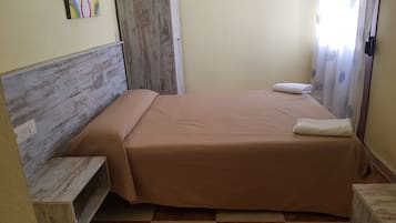 Un dormitorio pequeño y ordenado con cabecera de madera, una cama individual con colcha marrón, una mesita de noche y una obra de arte colgada en la pared.