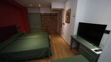 Un dormitorio con dos camas, un televisor y una pared de piedra.