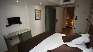 A bedroom with a bed, a desk, a television, and a door leading to a bathroom. - Boutique Hotel Castilla (Soria)